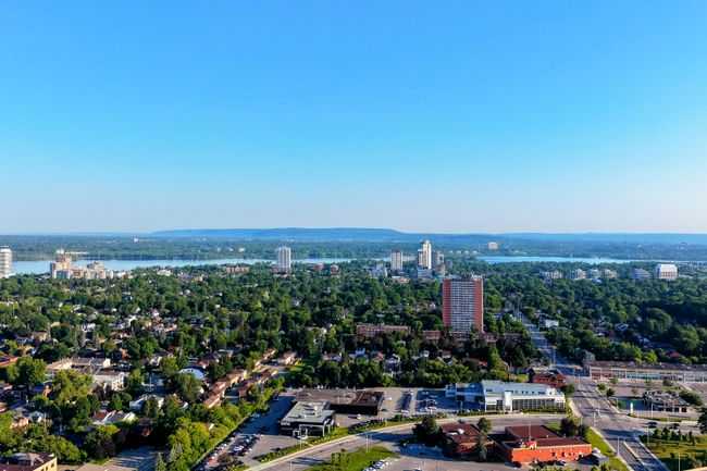 A stunning aerial view of a cityscape with river, urban areas, and lush forests under a clear blue sky