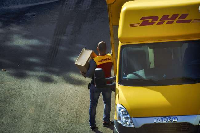 DHL deliveryman taking a package out of a DHL van