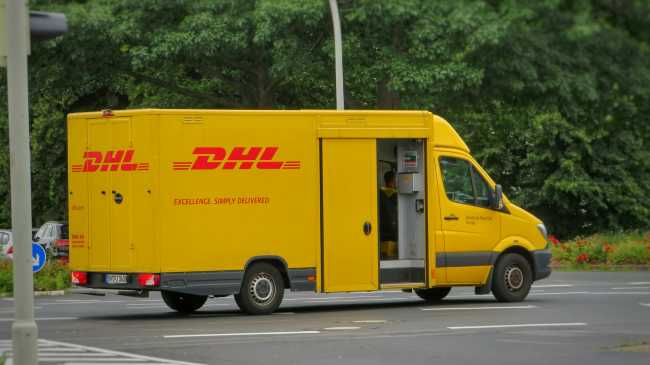 A DHL van parked in a parking lot with the side doors opened
