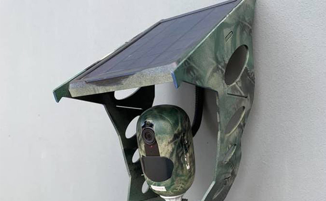 A security camera is painted in camouflage to hide it from its surroundings